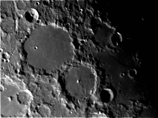 Lunar surface featuring multiple craters with varying sizes and depths.