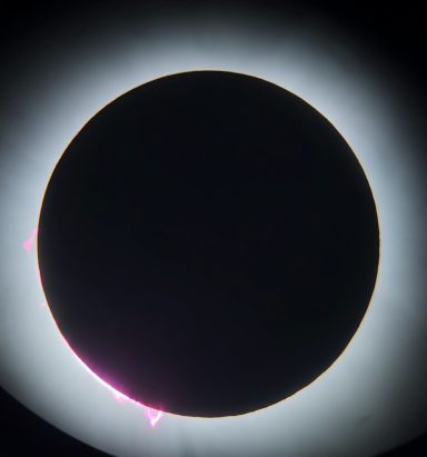 Solar eclipse with a darkened moon silhouette and bright coronal edges.