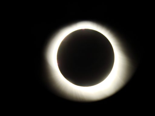 Total solar eclipse showing a halo around the darkened moon against a black sky.